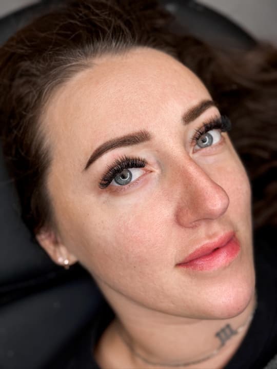 Woman showcasing her new permanent makeup with natural, flawless results